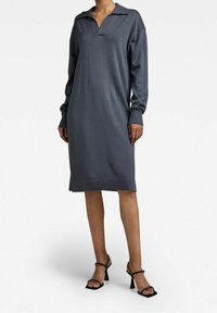 Långärmad, kragad klänning i mörkgrått stickat material, med en avslappnad passform och ribbad nederkant. Bärs med svarta remsandaler med klack.