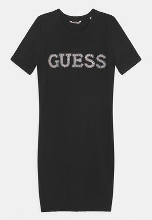 Czarna krótka sukienka dzianinowa z prążkowanym dekoltem i rękawami, z napisem "GUESS" w dużych, błyszczących literach z cyrkonii na piersi.