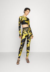 Crni i zlatni komplet s dugim rukavima i tajicama, sa bogatim baroknim uzorcima i prilagođenim dizajnom. Glatka, rastezljiva tkanina.