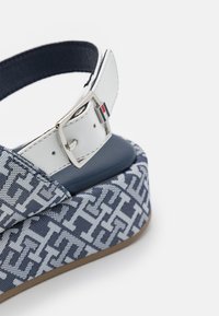 Blåmönstrad platå sandal med vävd design, vit justerbar ankelrem med silverspänne och en texturerad sula.