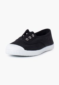 Baskets slip-on en toile noire avec semelle et embout en caoutchouc blanc, comportant quatre œillets métalliques de chaque côté sans lacets.