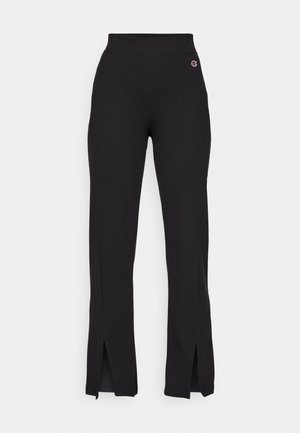 Black fabric pants with a high waistband, featuring side slits at the hem and a small embroidered logo on the upper left side.