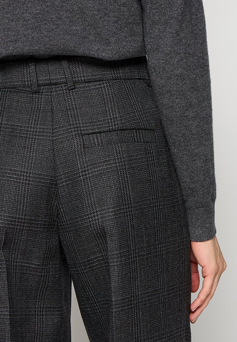 Grijze woltrui gecombineerd met zwart-grijs geruite broek met achterzak, aangepaste pasvorm en een gladde textuur.