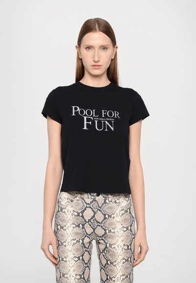 Maglietta nera corta con maniche corte, con la scritta bianca "POOL FOR FUN" sul davanti. Abbinata a pantaloni a fantasia con stampa di serpente.