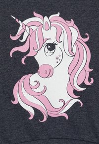 Un tessuto grigio scuro presenta una grande grafica di un unicorno, con un viso bianco, una criniera rosa e un corno a spirale. I dettagli notevoli includono grandi occhi espressivi.