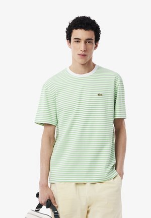 Camiseta de manga corta a rayas verdes y blancas con cuello redondo y pequeño detalle de logo en el pecho. Tejido de algodón y corte relajado.