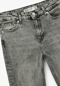 Donkergrijze denim jeans met een flare fit, met een vervaagde textuur. Inclusief zijzakken en een knoopsluiting met een merklabel.