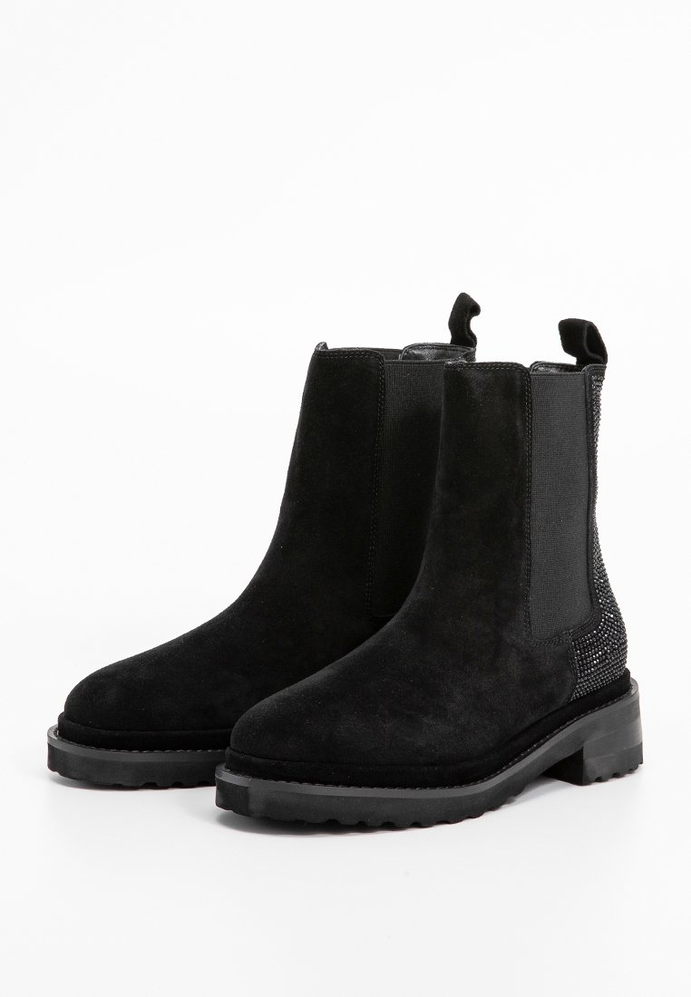 Bottines en suede noir avec des panneaux latéraux élastiques, un accent texturé à l'arrière et une semelle en caoutchouc épaisse. Talon bas et languette pour un enfilage facile.