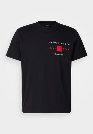 Juodas medvilninis marškinėliai su balta ir raudona spausdinta grafika, kurioje yra tekstas "Calvin Klein" ir "since 1968" virš raudono kvadrato.