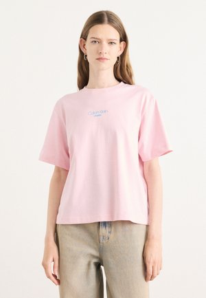 Roze katoenen T-shirt met korte mouwen en een ronde hals; voorzien van een blauw geborduurd "Calvin Klein Jeans" logo in het midden op de borst.
