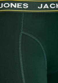 Gros plan d’un boxer vert foncé avec des coutures visibles et une ceinture montrant partiellement le nom de la marque « JONES JACK ».