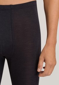 Sorte leggings med en glat tekstur, der har en subtil glans og en tætsiddende pasform. Taljen sidder stramt øverst med elegante syninger.
