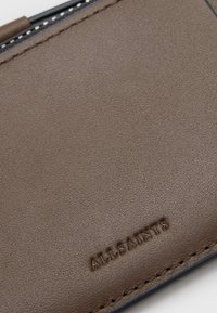 Portafoglio in pelle marrone con texture liscia, logo "ALLSAINTS" impresso e cuciture contrastanti lungo i bordi.
