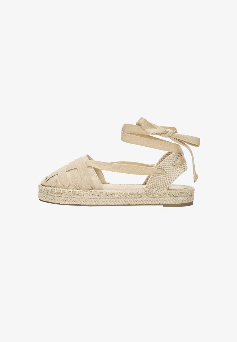 Beige vævet espadrille sandal med krydsede stropper, ankelbind og en flettet jute sål. Åben tå-design med en flad gummihæl.
