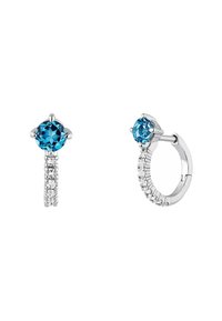 Pendientes de aro de plata con una piedra preciosa azul central, que presentan una fila de piedras claras más pequeñas a lo largo del aro. Forma redonda, acabado pulido.