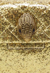 Gold glitter clutch bag with a textured surface, featuring a decorative metallic clasp shaped like a feather with black accents.