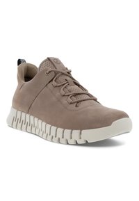 Világosbarna, sima sneaker, amely velúrból készült, texturált felsőrésszel. Rugalmas, hullámformájú fehér gumitalppal és fűzőkkel rendelkezik.