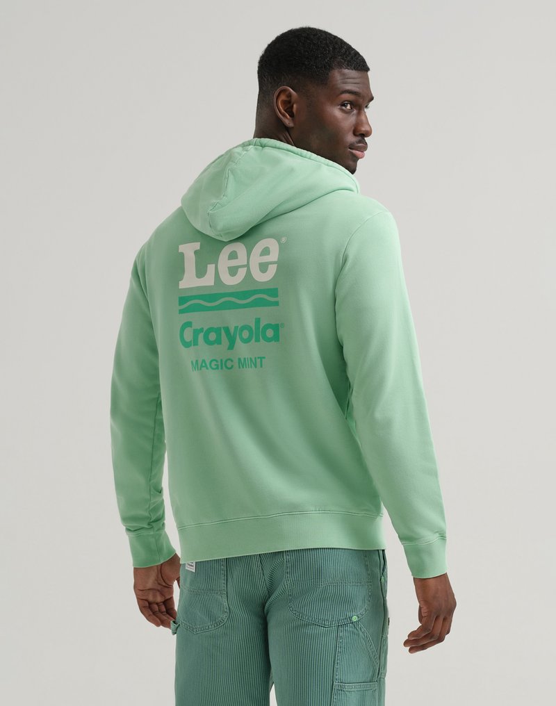 Uomo di profilo che indossa un hoodie verde menta con il testo "Lee Crayola Magic Mint" sulla schiena e pantaloni a righe turchesi.