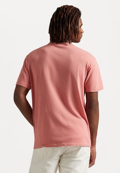 Korte mouwen, ronde hals T-shirt in pastelroze katoen. Beschikt over een relaxte pasvorm en zachte textuur, met zichtbare stiksels aan de zoom en de mouwen.