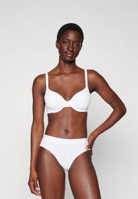 Weißes BH- und hochgeschnittenes Slip-Set. Glattes Material, nahtloses Design, verstellbare Träger, weicher Bund und minimalistischer Stil.