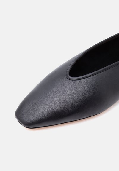 Μαύρο επίπεδο παπούτσι από δέρμα με τετράγωνη μύτη, με ομαλή υφή και χαμηλή περπατημένη περιοχή σε ανοιχτό φόντο.