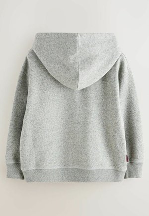 Grå hoodie med en mjuk, texturerad tyg, en huva och ribbade cuffar och nederkant. En liten logotag är synlig på nedre vänstra sidan.