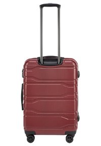 Valise rigide rouge avec surface texturée, poignée noire extensible, double roues et zips encastrés. Forme compacte et rectangulaire.