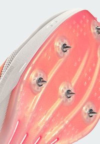 Sleek shoe sole featuring a pink and white design with metallic spikes, textured surface, and prominent grooves for traction.