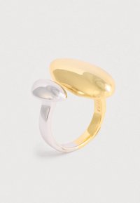 Avoin rengas, jossa on yksi suuri kultainen soikea ja yksi pienempi hopeinen soikea valkoista taustaa vasten.