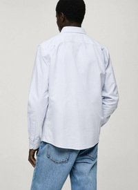Helles blaues, gestreiftes Hemd mit klassischem Kragen, langen Ärmeln und lockerer Passform, kombiniert mit hellblauen Jeans.