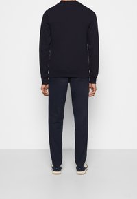 Marinblå sweatshirt med långa ärmar och ribbade muddar och fåll, kombinerad med matchande marinblå byxor. Slät tyg, enkel design, inga synliga mönster.