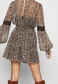 Doorzichtig lange mouwen bloemenjurk met een cinched taille, kantafwerking op de mouwen, uitlopende rok en een keyhole opening aan de achterkant.