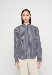 Long-sleeve button-up shirt in navy and white stripes, classic collar, button closure, and tailored fit with cuffed sleeves.