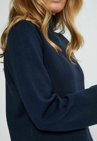 Maglione a dolcevita navy realizzato in morbido tessuto a maglia con maniche lunghe, design aderente e una texture liscia. Stile minimalista senza motivi.