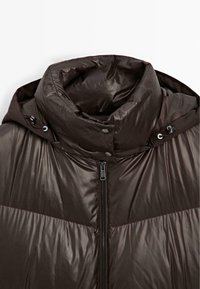 Kurtka puchowa w błyszczącym ciemno-brązowym materiale, posiadająca wysoki kołnierz, zamek błyskawiczny z przodu oraz napy na kołnierzu do regulacji.