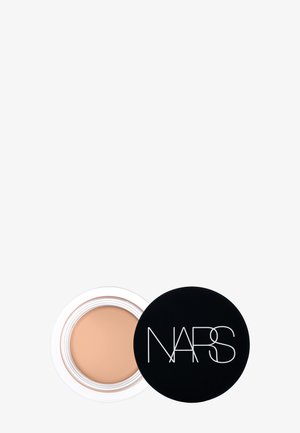 Pot ouvert de correcteur crème beige avec un couvercle noir portant le logo NARS sur un fond blanc uni.