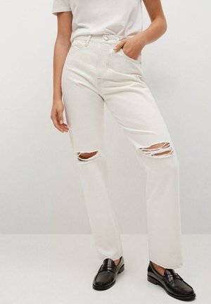 Kermanväriset, korkeavyötäröiset farkut, joissa on kaksi revittyä polvea ja suorat lahkeet. Yhdistetty mustiin loafer-kengiin ja valkoiseen t-paitaan.