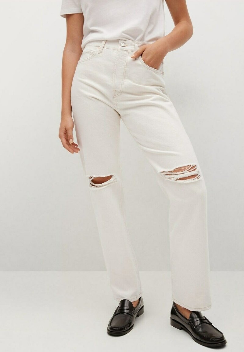 Krémové džíny s vysokým pasem, s dvěma roztrženými koleny a rovnými nohavicemi. Sestavené s černými mokasíny a bílým tričkem.