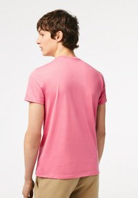 Rosa kortärmad t-shirt i mjukt bomullsmaterial, rund halsringning och avslappnad passform. Enkelt design utan mönster eller accentuerande detaljer.