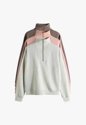 Trois pull-overs exposés : gris clair, rose et marron foncé. Chacun présente un col haut avec une fermeture éclair à l'avant et une texture douce.