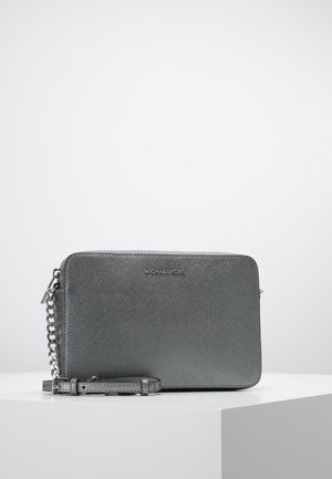 Graue, strukturierte Lederclutch von Michael Kors mit silberner Kettenriemen und Reißverschluss, die auf einer weißen Oberfläche vor einfachem Hintergrund liegt.