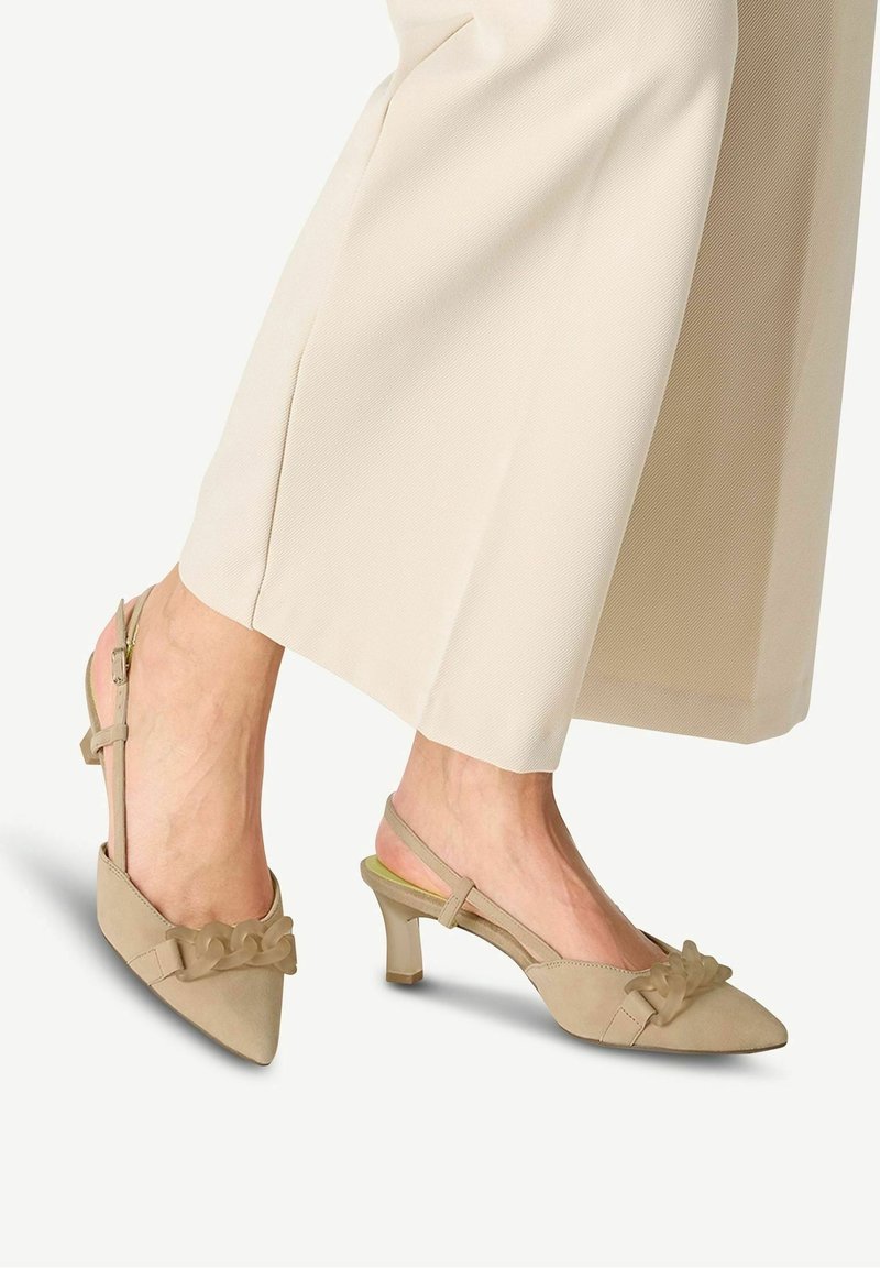 Talons slingback beiges avec un bout pointu, présentant un nœud texturé décoratif à l'avant et un talon bloc modérément surélevé.