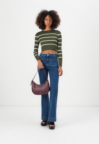 Mørkegrønn ribbet cropped genser med hvite striper, høytlivede blå jeans og en burgunder lærveske. Svart plattform sandaler.