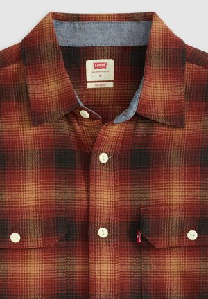 Camisa de cuadros rojos y negros con cuello de mezclilla, dos bolsillos en el pecho con botones y botones blancos. La etiqueta dice "Levi's", talla mediana.