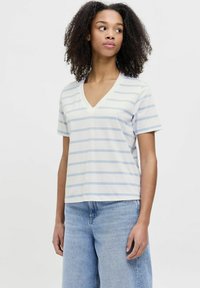 Camiseta blanca de cuello en V con rayas horizontales azul claro, de manga corta y corte holgado, combinada con vaqueros de cintura alta azul claro.