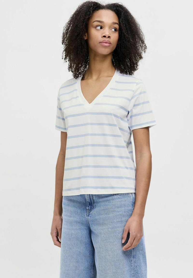Camiseta blanca de cuello en V con rayas horizontales azul claro, de manga corta y corte holgado, combinada con vaqueros de cintura alta azul claro.
