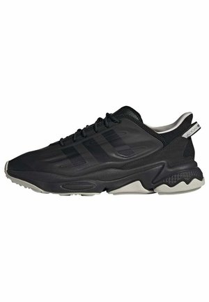 Czarny niskoprofilowy sportowy sneaker z teksturowaną podeszwą, sznurowany z przodu oraz subtelnym wzorem trzech pasków z boku.