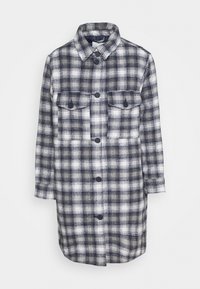 Giacca a camicia a quadri in blu navy, bianco e grigio. Presenta un colletto, maniche lunghe, due tasche sul petto con bottone e bottoni frontali. Tessuto dalla consistenza morbida.