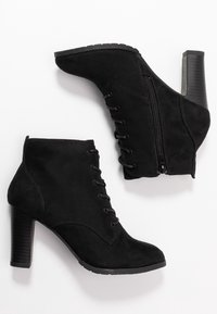 Botines negros de ante hasta el tobillo con un tacón alto y cuadrado, que incluyen cordones en la parte delantera y un cierre lateral para un acceso fácil. Textura suave y diseño elegante.