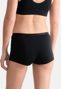 Boxers en coton noir avec une ceinture élastique lisse, présentant un design simple sans motifs ni accents visibles.